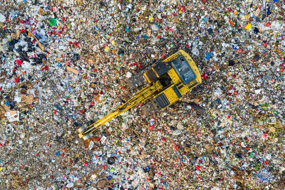 do clothes go in garbage or recycle based on this image of a crane surrounded by thousands of tonnes of garbage in a landfill