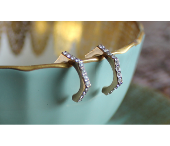 Gold studded diamond earrings hanging from a blue teacup