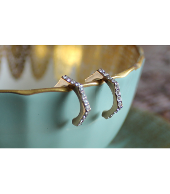 Gold studded diamond earrings hanging from a blue teacup