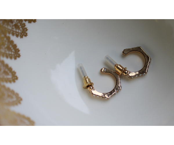 Gold studded diamond earrings inside a teacup